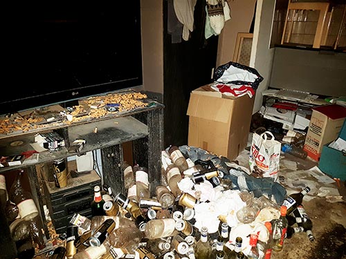 Salon encombré de déchets, bouteilles et objets avant nettoyage d'un logement touché par le syndrome de Diogène