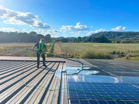 Technicien équipé, nettoyant panneaux photovoltaïques en toiture